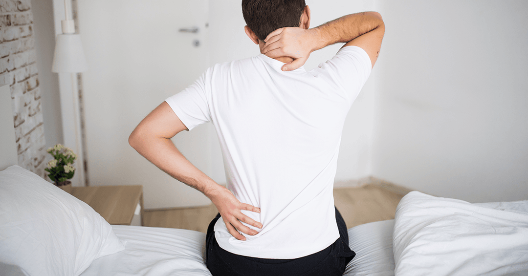 Man holding his back as the old Mattress is causing pain